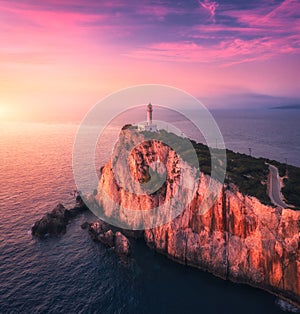 Lighthouse on the mountain peak at colorful sunset in summer