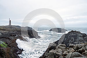 Lighthouse next to Nato base in Stokksnes peninsula next to the city of Hofn in Iceland. Waves crash ashore with overcast sky