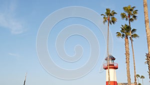 Lighthouse, palm trees and blue sky. Red and white beacon. Waterfront harbor village. California USA