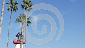 Lighthouse, palm trees and blue sky. Red and white beacon. Waterfront harbor village. California USA