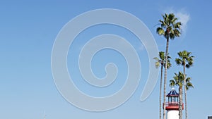 Lighthouse, palm trees and blue sky. Red and white beacon. Waterfront harbor village. California USA