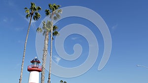 Lighthouse, palm trees and blue sky. Red and white beacon. Waterfront harbor village. California USA