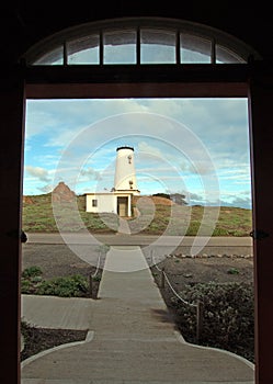 Lighthouse at Piedras Blancas point as seen from fog signal building under sunset clouds on the Central Coast of California