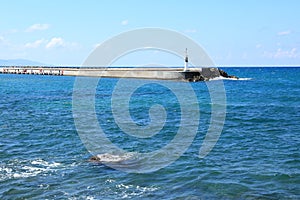 Lighthouse on pier with groyne in blue sea