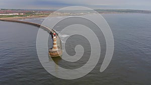 A Lighthouse and Pier at the Mouth of a Harbour