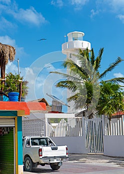 Lighthouse in Puerto Morelos. Street view with white car, palms and fence. Wallpaper or background. Yucatan. Quintana roo.