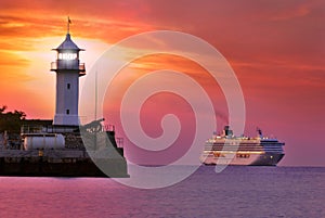 Lighthouse in red twilight with ship