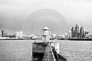 Lighthouse in reykjavik, iceland. Lighthouse tower and stone pier in sea. Seascape and skyline on grey sky. Architecture