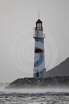 Lighthouse among the rising waves of a storm in Lodos. Turgutreis, Bodrum.