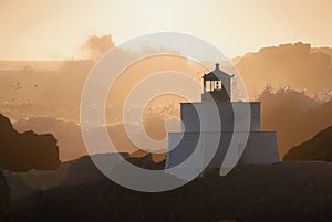 Lighthouse on Rock with Crashing Waves at Sunset