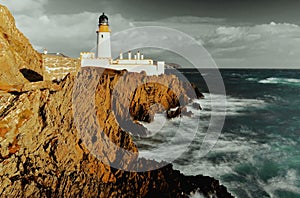 A lighthouse with rocks and the ocean in the background