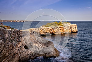 Lighthouse on rocks with sea and waves. Sunny day with blue sky. Porto Cristo, Mallorca, Spain