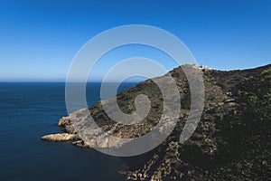 Lighthouse on rocky cliffs in deep blue ocean bay in the natural park `Serra Gelada` in Albir, Spain