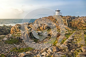 Lighthouse on a rocky shore during a sunset