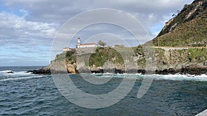 A lighthouse is on a rocky shoreline Cudillero, Asturias photo