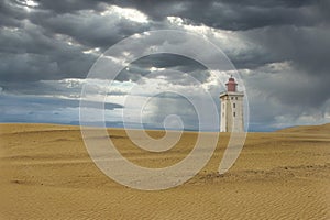 Lighthouse on a sand dune on background of gloomy clouds