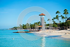 Lighthouse on a sandy tropical island with palm trees.