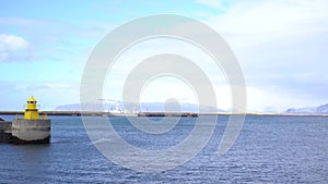 Lighthouse on sea pier in Reykjavik Iceland. Lighthouse yellow bright tower at sea shore. Sea port navigation concept