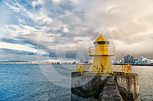 Lighthouse on sea pier in reykjavik iceland. Lighthouse yellow bright tower at sea shore. Sea port navigation concept