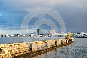 Lighthouse on sea pier in reykjavik iceland. Lighthouse yellow bright tower at sea shore. Seascape and skyline with
