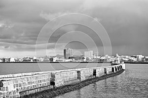 Lighthouse on sea pier in reykjavik iceland. Lighthouse yellow bright tower at sea shore. Seascape and skyline with