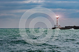 Lighthouse searchlight beam through marine air. Lighthouse In Stormy Landscape - Leader And Vision Concept