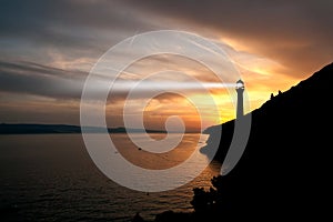 Lighthouse searchlight beam through marine air at night.