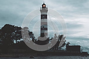 Lighthouse shines near the shore at sunset