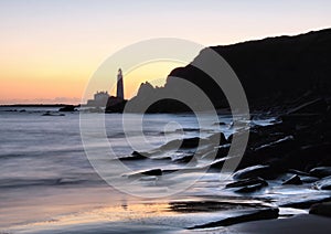 Lighthouse on shore at sunset