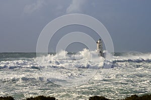 Lighthouse shrouded in waves during a storm in the Mediterranean.