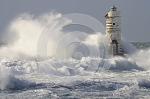 Lighthouse shrouded in waves during a storm in the Mediterranean.