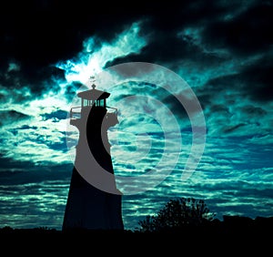 Lighthouse silhouette against ominous sky.