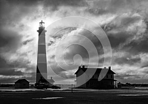 Lighthouse silhouetted in morning sunrise and stormclouds