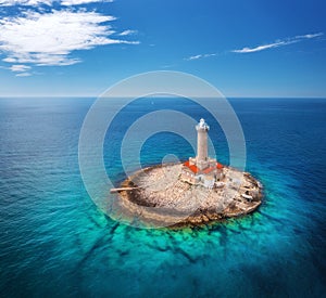 Lighthouse on smal island in the sea at sunny day in summer