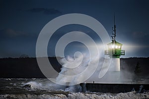 Lighthouse during storm in splashing spray at night on the Baltic Sea, Travemuende in the Luebeck bay, copy space photo