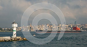 Lighthouse in the strait of Bosporus against the background of the city of Istanbul, Turkey and a oil tanker.