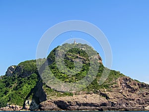 Lighthouse on the top of a greenish mountain