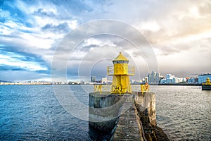 Lighthouse tower on stone pier in reykjavik, iceland. Lighthouse in sea. Seascape and skyline on cloudy sky. Architecture structur