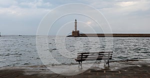Lighthouse at Venetian port, afternoon in Old Town of Chania Crete, Greece. Bench gets wet from sea