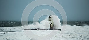 The lighthouse of the Mangiabarche shrouded by the waves of a mistral wind storm