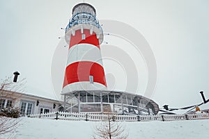 Lighthouse in winter in a fishing village, lighthouse in a blizzard