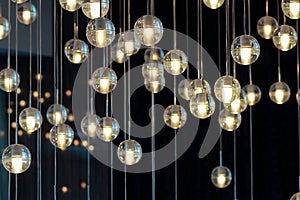 Lighting balls on the chandelier in the lamplight, light bulbs hanging from the ceiling, lamps on the dark background, selective