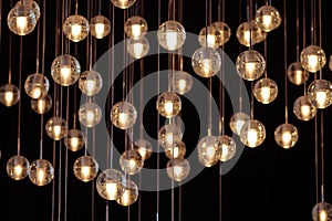 lighting balls on the chandelier in the lamplight, light bulbs hanging from the ceiling, lamps on the dark background, selective