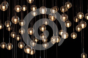 Lighting balls on the chandelier in the lamplight, light bulbs hanging from the ceiling, lamps on the dark background, selective