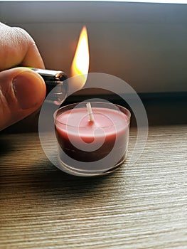 Lighting candle with a lighter. Hand holding lighter with flame.