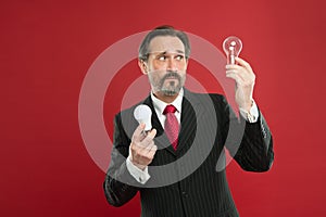 Lighting choices to save money. Man bearded consultant formal suit hold light bulb on red background. Symbol of idea