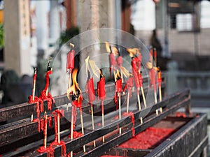 Lighting an red incense stick with taper candle in the Chinese temple, pay respect to god