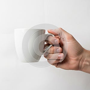 Lighting is soft, creating subtle shadows on the hand and mug,