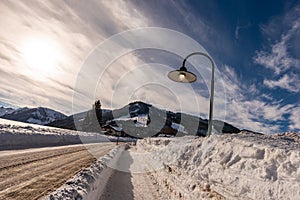 Lighting street lamp during the day on a snowy, empty street in winter. Waste of energy, unfriendly to the environment.