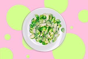 Lightly fried brussels sprouts on a white plate on the creative futuristic neon green and pink color drop with rounds
